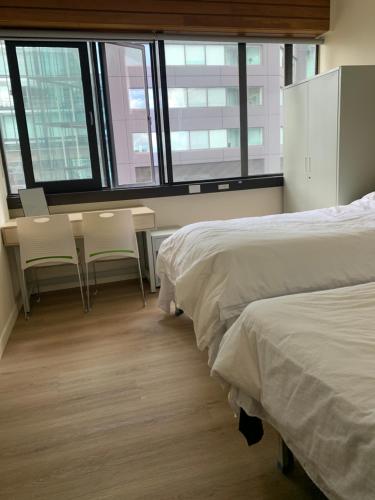 a bedroom with two beds and a table and chairs at Garden Hostel in Auckland
