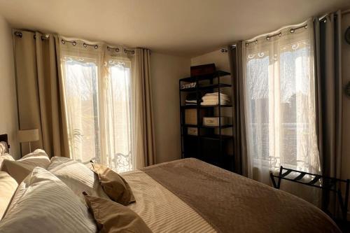 a bedroom with a bed and two windows at Appt de 50m2 Stade de France Canal Saint-Denis in Saint-Denis