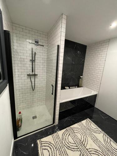 a bathroom with a shower and a black and white at L'Olivier in Beuzeville