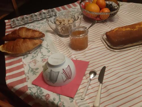 a table with bread and croissants and a bowl of oranges at L'Olivier in Beuzeville