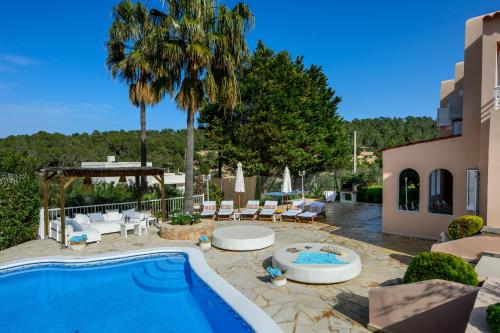 un patio trasero con piscina y palmeras en Villa Cas Puig - Beach of Portinatx, en Portinatx