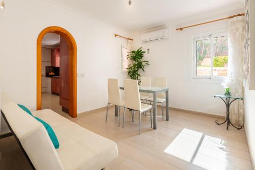 una sala de estar blanca con mesa y sillas en Villa Cas Puig - Beach of Portinatx en Portinatx