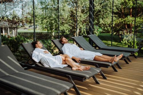 two people laying in lounge chairs on a deck at Artis Loft Hotel in Radziejowice