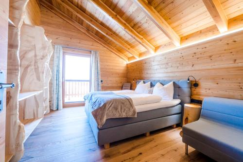 1 dormitorio en una cabaña de madera con 1 cama y 1 sofá en Hochleben-Chalets am Erlebnisbauernhof Steinerhof en Liebenfels