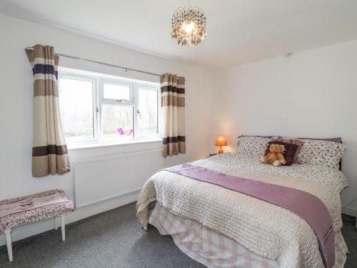 a bedroom with a bed with a teddy bear on it at Bear Lake Lodge in Alderwasley