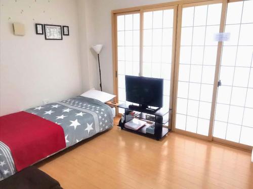 een slaapkamer met een bed en een flatscreen-tv bij abc OSAKA in Osaka