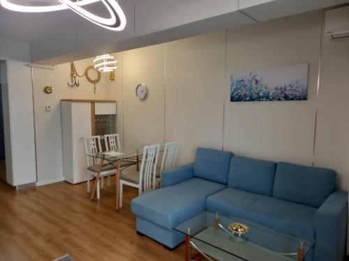 Una sala de estar con un sofá azul y una mesa. en Promenada Sea View with private parking, en Mamaia Nord – Năvodari