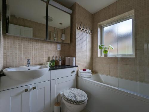 a bathroom with a sink and a tub and a toilet at Cosy house with a garden in London