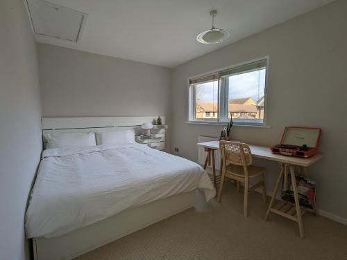 a bedroom with a bed and a desk with a computer at Cosy house with a garden in London