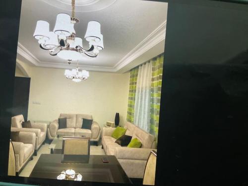 una sala de estar con sofás y una lámpara de araña. en Appartamento bello e elegante in west Amman, en Amán