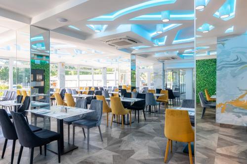 a dining room with tables and yellow chairs at Thermal Hotel Garden in Hajdúszoboszló