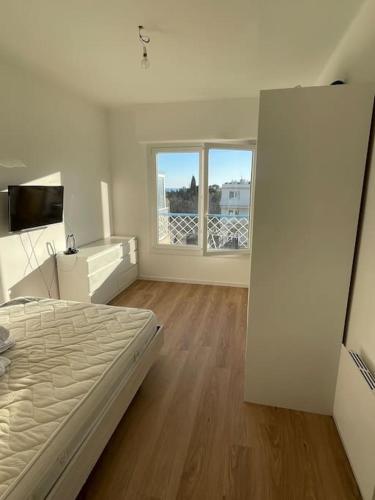 ein weißes Schlafzimmer mit einem Bett und einem großen Fenster in der Unterkunft Appartement la Seyne sur mer in La Seyne-sur-Mer