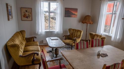 uma sala de estar com cadeiras, uma mesa e janelas em Hótel Djúpavík em Djupavik