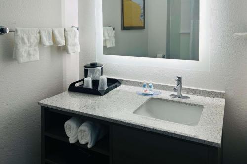 La salle de bains est pourvue d'un lavabo, d'un miroir et de serviettes. dans l'établissement Comfort Inn & Suites Wylie, à Wylie