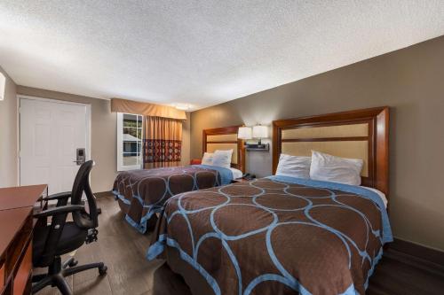 a hotel room with two beds and a desk at Rodeway Inn Charlotte Airport Area in Charlotte