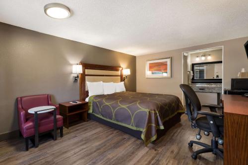 a hotel room with a bed and a desk and chairs at Rodeway Inn Charlotte Airport Area in Charlotte