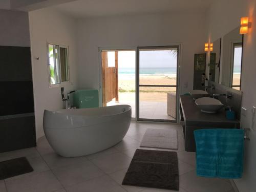 Vila Mare - Praia de Chaves frontline في Cabeçadas: حمام به مغسلتين وحوض استحمام كبير