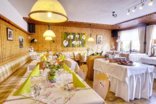 a restaurant with white tables and chairs and a yellow ceiling at Pension Fohrenberg in Ewattingen