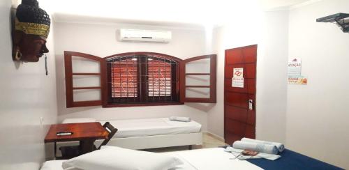 a room with two beds and a table and a window at Pousada Estrela Mare in São Sebastião