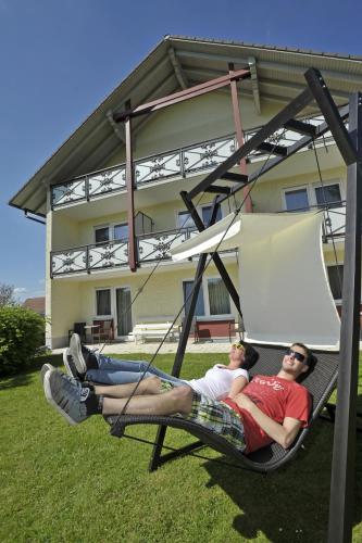 two people laying in a hammock in front of a house at Pension Fohrenberg in Ewattingen