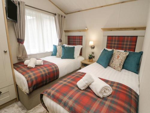 two beds in a hotel room with towels on them at Lindale Lodge in Carnforth