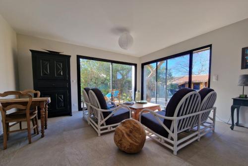 a living room with chairs and a table and windows at Les Callunes chambres d'hôtes et location meublée à 800 m de la plage ! in Lanton