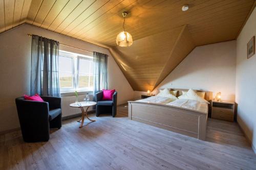 RauhenebrachにあるPension Oppeltのベッド1台、椅子2脚、窓が備わる客室です。