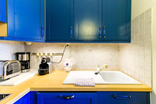 a kitchen with blue cabinets and a sink at SELECT'SO HOME - Appartement Vue mer & Pieds dans l'eau - ESTEL-F in Le Lavandou