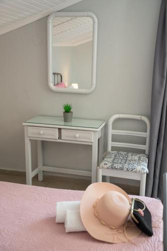 a hat sitting on top of a bed with a mirror at Minas Apartments in Divarata