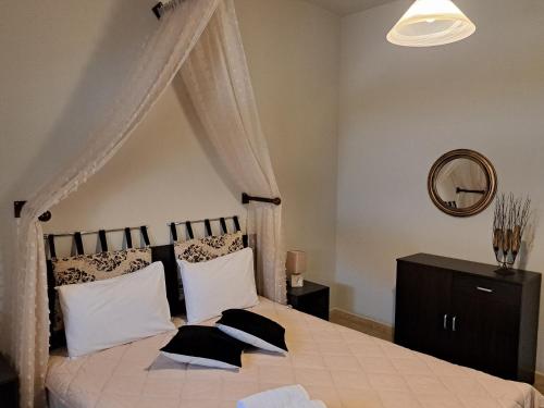 a bedroom with a canopy bed with pillows and a mirror at Guesthouse Aelia in Kato Loutraki