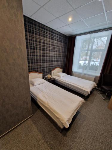 two beds in a room with a window at Hotel Kārklu Muiža in Jelgava
