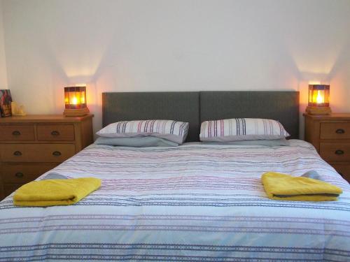 a bedroom with a bed with two yellow towels on it at Beech Tree Cottage with free parking in Bury Saint Edmunds