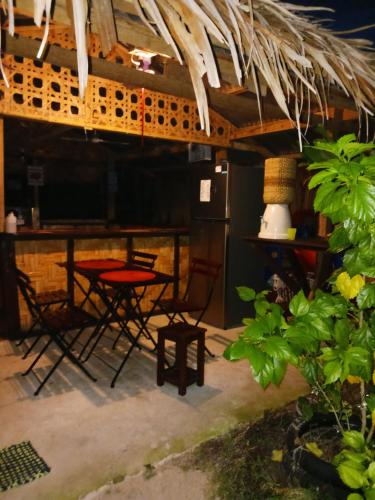 patio ze stołami i krzesłami pod dachem krytym strzechą w obiekcie Weeroona Huts Homestay Pacifico w mieście San Isidro