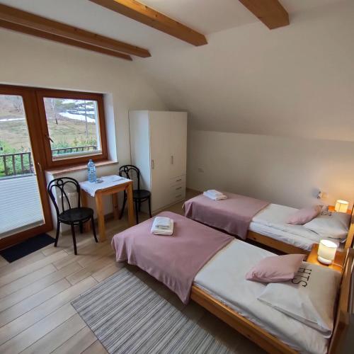 a bedroom with two beds and a table and a window at Hołdysówka przy Gondoli in Szczyrk