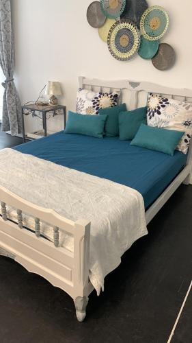 a white bed with blue pillows on top of it at Studio Cosy avec terrasse. in Boyer