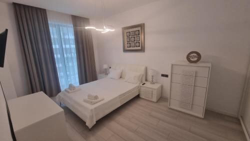 a white bedroom with a bed and a window at Anateea by the Sea in Mamaia