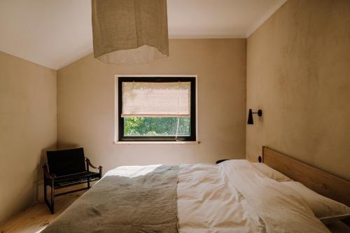 a bedroom with a bed and a window and a chair at Gniazdowo nad rzeką - dom z sauną i masażem in Łochów