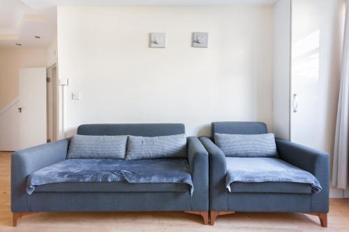 a blue couch with two pillows in a living room at Comfortable Budget Apartment Next To Eurostar International - Kings Cross & Euston Station in London