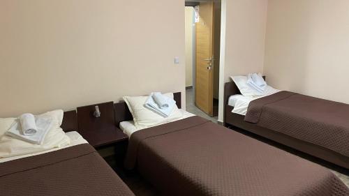 una camera d'albergo con tre letti e asciugamani di Garni Hotel Lion a Jagodina