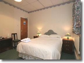 ポートランドにあるポートランド ロッジのベッドルーム1室(白いベッド1台、テーブル2台、ランプ2つ付)