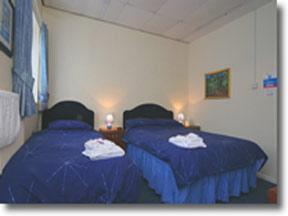 two beds in a room with blue sheets and towels at Portland Lodge in Portland