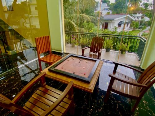 a balcony with a table and chairs and a swimming pool at Nirosha Guest House in Galle