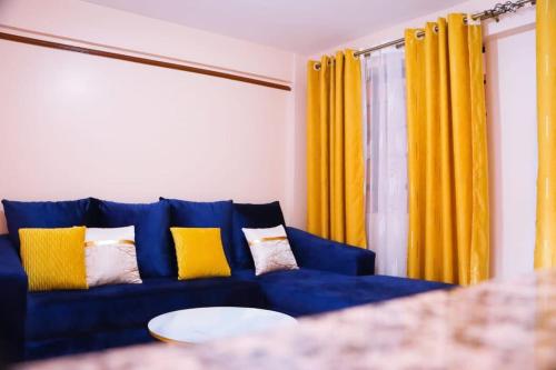 un sofá azul en una sala de estar con cortinas amarillas en Santaq villas apartment en Nairobi