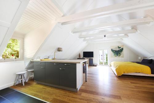 Biała sypialnia na poddaszu z łóżkiem i kuchnią w obiekcie Apartments Wassermühle Stenten w mieście Alt Duvenstedt