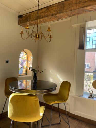 a dining room with a round table and yellow chairs at B&B Het Molenhuisje Winschoten - met woonkamer & keuken in Winschoten