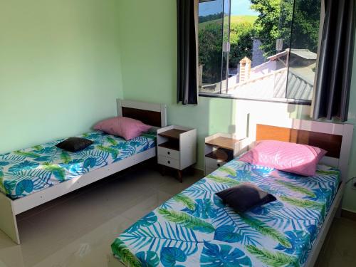 2 Betten in einem Zimmer mit Fenster in der Unterkunft Casa e área Gourmet. Cardoso Moreira-RJ in Cardoso Moreira