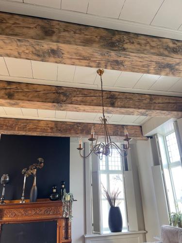 a living room with a wooden ceiling and a window at B&B Het Molenhuisje Winschoten - met woonkamer & keuken in Winschoten
