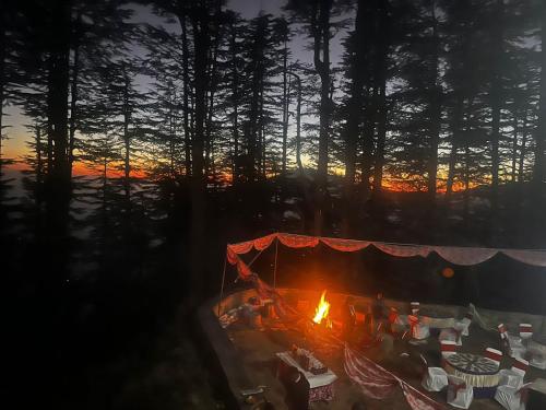 a fire in a tent with a sunset in the background at Norvin Homes in Shimla