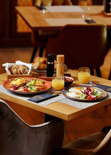a table with two plates of food and glasses of orange juice at Chop Old House Hotel in Velika Gorica