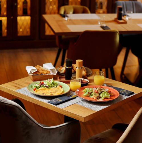 a table with two plates of food and glasses of orange juice at Chop Old House Hotel in Velika Gorica